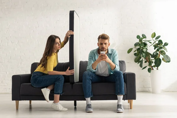 Jovem Segurando Modelo Smartphone Enquanto Namorado Conversando Sofá — Fotografia de Stock