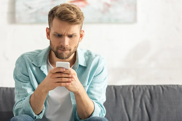 Hombre Confundido Mirando Teléfono Inteligente Sofá Casa — Foto de Stock