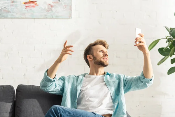 Bonito Homem Usando Smartphone Enquanto Sentado Sofá Sala Estar — Fotografia de Stock