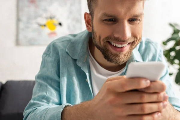 Oturma Odasındaki Kanepede Akıllı Telefon Kullanarak Gülümseyen Bağımlı Bir Adamın — Stok fotoğraf