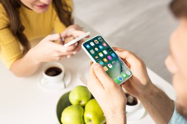 KYIV, UKRAINE - 21 Şubat 2020: Kahvaltıda iPhone ve kız arkadaşının yanında iPhone kullanan erkeğin seçici odak noktası 