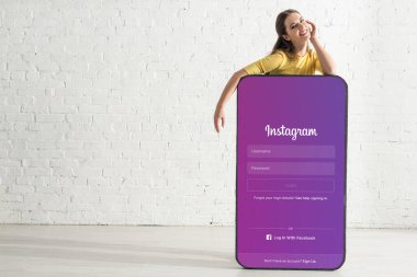 KYIV, UKRAINE - 21 Şubat 2020: Instagram yakınlarında kameraya bakan gülümseyen kız akıllı telefonun büyük modelinde 