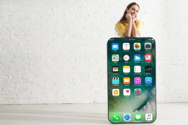 KYIV, UKRAINE - 21 Şubat 2020: Akıllı telefonun yanında iPhone ekranlı kameraya bakan pozitif kız  