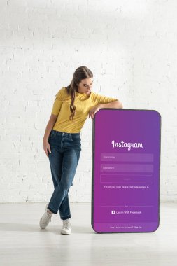KYIV, UKRAINE - 21 Şubat 2020: Güzel kadın Instagram uygulamasına bakıyor evde akıllı telefonun büyük modeli
