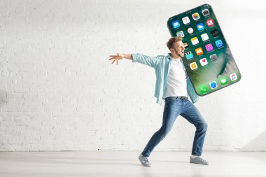 KYIV, UKRAINE - 21 Şubat 2020: Neşeli adam iPhone ekranlı akıllı telefon modelini tutarken yüzünü çeviriyor 