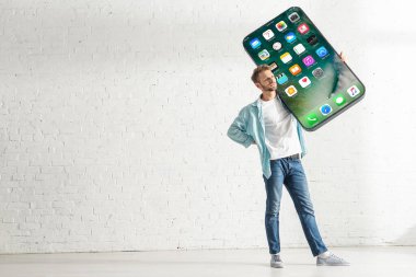 KYIV, UKRAINE - 21 Şubat 2020: Elinde iPhone ekranlı akıllı telefonun kalça tutma modeli olan genç adam 