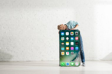 KYIV, UKRAINE - 21 Şubat 2020: Gözleri kapalı gülümseyen adam iPhone ekranlı akıllı telefonun modelini kucaklıyor 