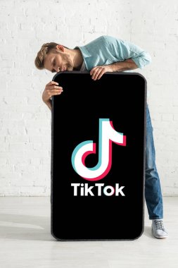 KYIV, UKRAINE - 21 Şubat 2020: Evde TikTok uygulaması ile akıllı telefonun modelini öpen adam 