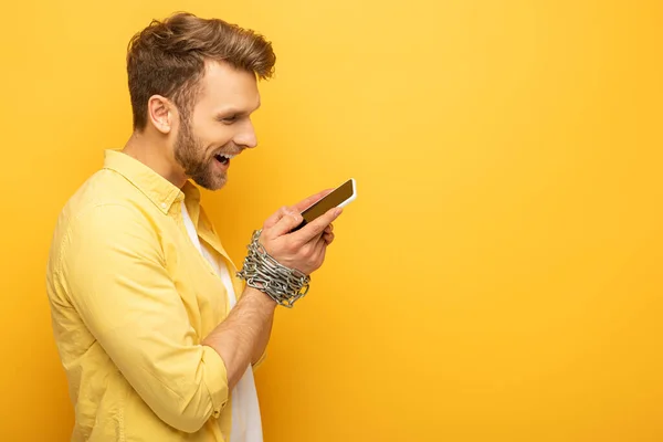 Side View Smiling Man Chain Hands Holding Smartphone Yellow Background — Stock Photo, Image