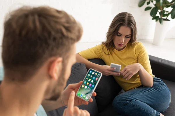 Kyiv Ukraine 2017年2月21日 男人在沙发上与女友聊天时使用带有Iphone屏幕的智能手机的选择性焦点 — 图库照片