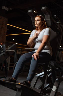 Kendine güveni tam şişman bir kız spor makinesinde otururken gözlerini kaçırıyor.