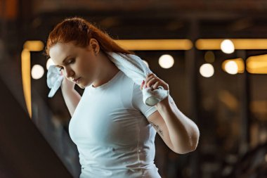 Güzel, kilolu bir kız havluyu tutarken spor yapıyor.