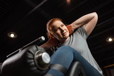 Düşük açılı, kaslı, kilolu bir kızın fitness makinesi üzerinde karın kası egzersizi yapması. 