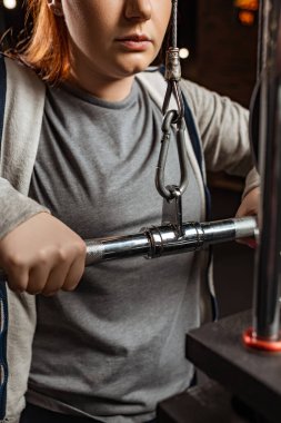 Kilolu bir kızın spor aleti üzerinde kol uzatma egzersizi yaptığı görüntüler.