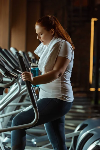 Cansada Chica Con Sobrepeso Sosteniendo Botella Deportiva Mientras Entrena Stepper — Foto de Stock