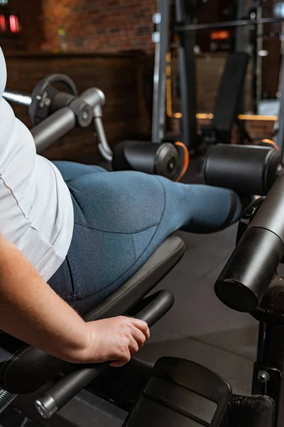Kilolu kızın fitness makinesinde bacak uzatma egzersizi yaptığı görüntüler.