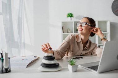 Zen taşı ve dizüstü bilgisayarla işyerinde oturan hayalperest iş kadını. 
