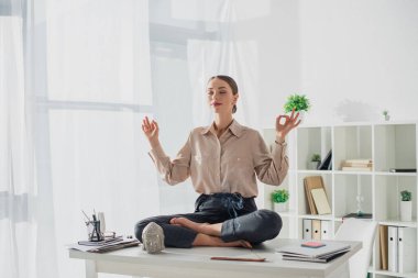 Çekici iş kadını Lotus 'ta meditasyon yapıyor. İş yerinde Buda kafası ve tütsü çubuğuyla Gyan Mudra ile poz veriyor.