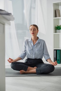 Çekici iş kadını Lotus pozisyonunda yoga yapıyor. Ofiste Gyan Mudra ile birlikte. 