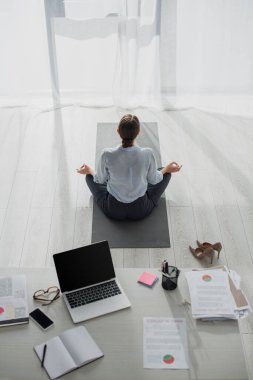 Nilüfer pozisyonunda yoga yapan iş kadınının arka görüntüsü. Ofiste Gyan Mudra ile. 