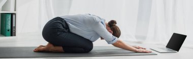 Çocuk Poz 'daki genç iş kadınının ofiste dizüstü bilgisayarında yoga derslerinin panoramik görüntüsü. 