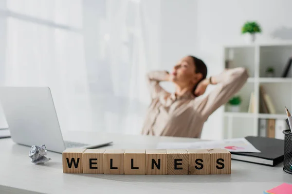 Selective Focus Businesswoman Relaxing Workplace Laptop Alphabet Cubes Wellness Word — Stock Photo, Image