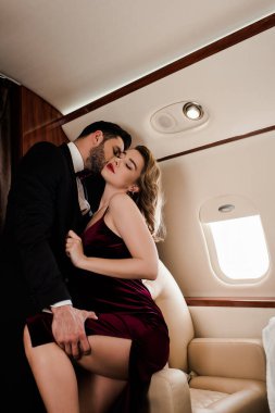Zarif bir adam bacağına dokunuyor ve uçakta tutkulu bir kadını öpüyor.