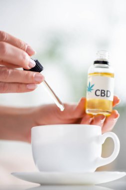 Olgun bir kadının çay bardağına bir damla cbd kattığı görüntüler. 