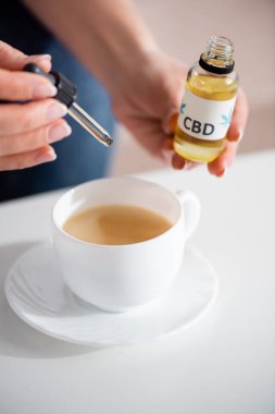 Yetişkin bir kadının çay fincanına cbd eklediği görüntüler.