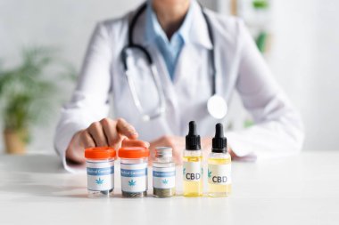 Doktorun tıbbi kenevir harfleriyle şişeyi işaret etmesi. 