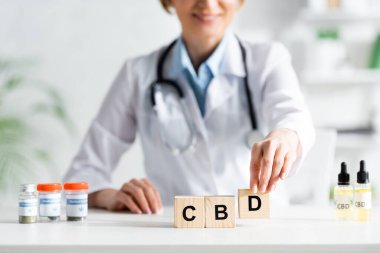 Beyaz önlüklü mutlu bir doktorun, uyuşturucunun yanında cd harfleri olan küplere dokunuşunun görüntüsü. 