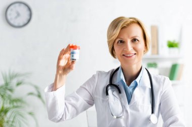 Beyaz önlüklü, elinde tıbbi kenevir yazısıyla mutlu ve olgun bir doktor. 