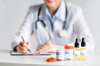 Doktorun yazdığı reçetenin yanında kurumuş marihuana, CBC ve tıbbi kenevir içeren şişeler seçici odak noktası 