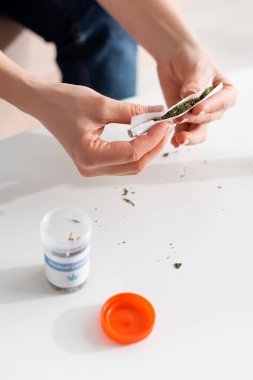 Olgun bir kadının elinde marihuanayla tıbbi kenevir harfleriyle şişenin yanında kağıt tutması. 