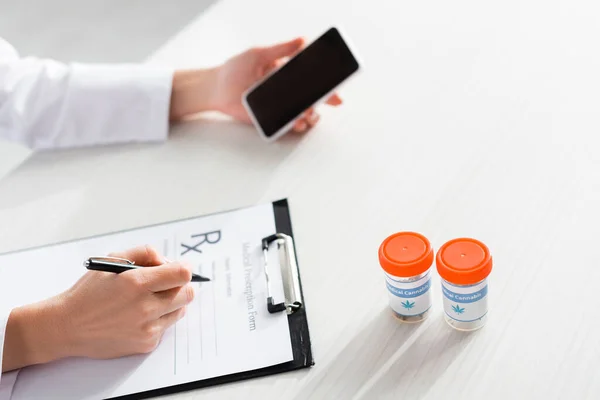 Cropped View Doctor Writing Prescription Bottles Medical Cannabis Holding Smartphone — Stock Photo, Image