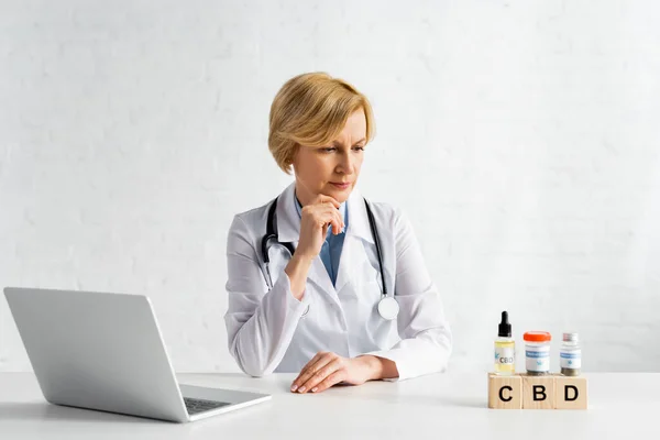 Mature Doctor Looking Cubes Cbd Lettering Bottles Medical Cannabis Laptop — Stock Photo, Image