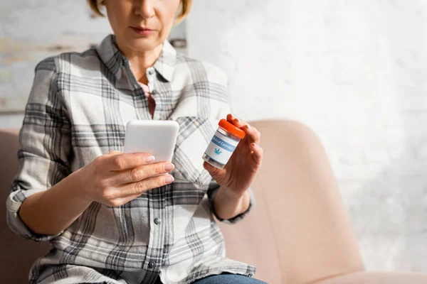 Cropped View Mature Woman Using Smartphone Holding Bottle Medical Cannabis — Stock Photo, Image