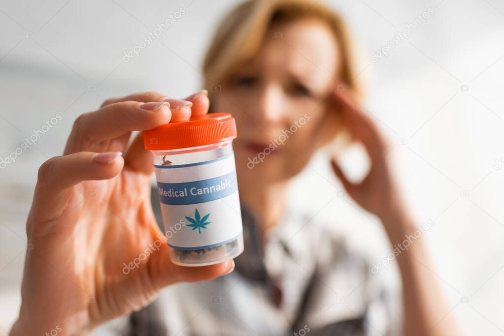 selective focus of mature woman holding bottle with medical cannabis lettering