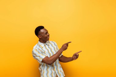 Sarı arka planda parmakları olan mutlu Afrikalı Amerikalı adam