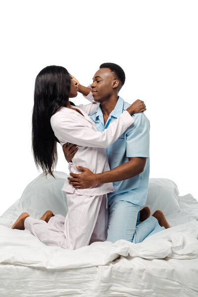 african american couple hugging in bed in pajamas isolated on white