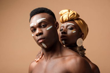 Bej rengi üzerinde poz veren seksi, çıplak afro bir çift.