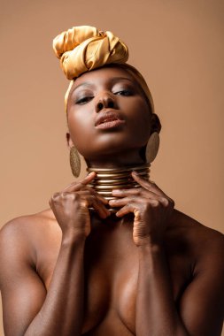 Bej rengi üzerinde yalnız poz veren seksi çıplak afro kadın.