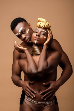 Bej rengi üzerinde yalnız poz veren seksi, çıplak afro bir çift.