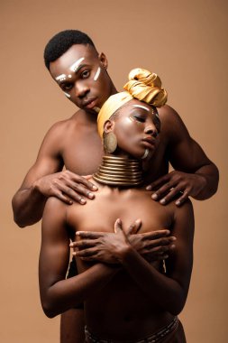 Bej rengi üzerinde yalnız poz veren seksi, çıplak afro bir çift.