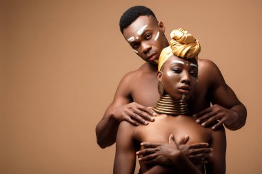 naked tribal afro couple posing on beige background clipart