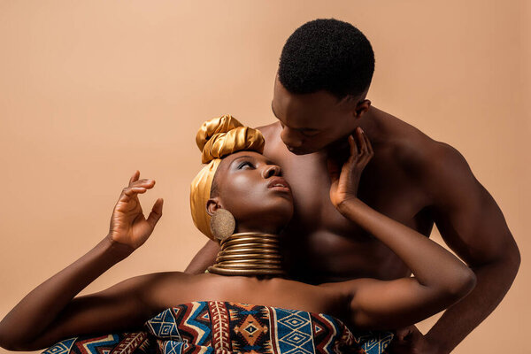 Sexy naked tribal afro woman covered in blanket touching man isolated on beige