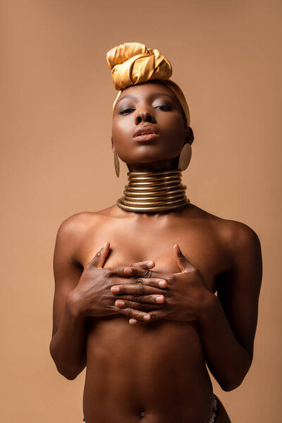 Sexy naked tribal afro woman posing isolated on beige