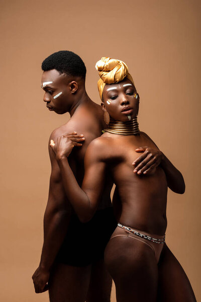 Sexy naked tribal afro couple posing isolated on beige