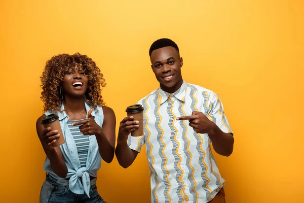 Happy African American Couple Pointing Paper Cups Yellow Colorful Background — Stock Photo, Image