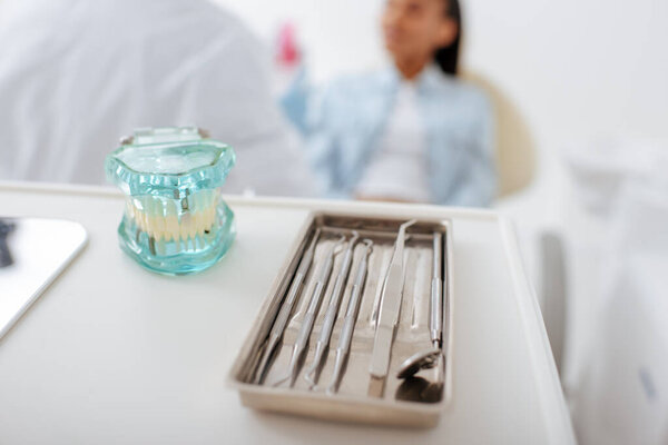 selective focus of teeth model and dental instruments near dentist and african american patient 